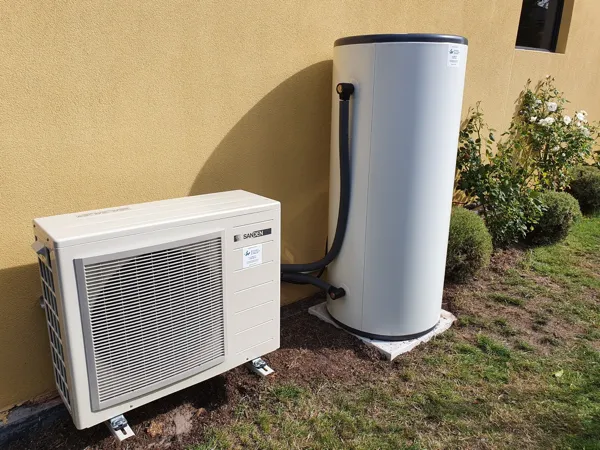 Hot water heat pump system installed at the side of a home.
